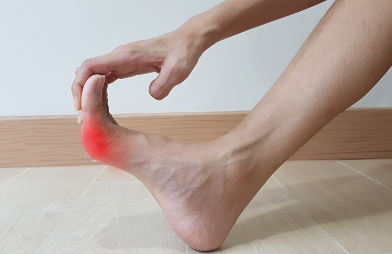 Hand holding on foot anatomy with red highlight on painful area. Toe pain may cause from bone fracture, tendinitis, ligament sprain, gout arthritis or bunion disease. medical symptom